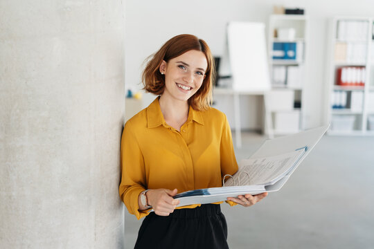 A woman smiling while looking at her laptop, representing a professional benefiting from AI training.